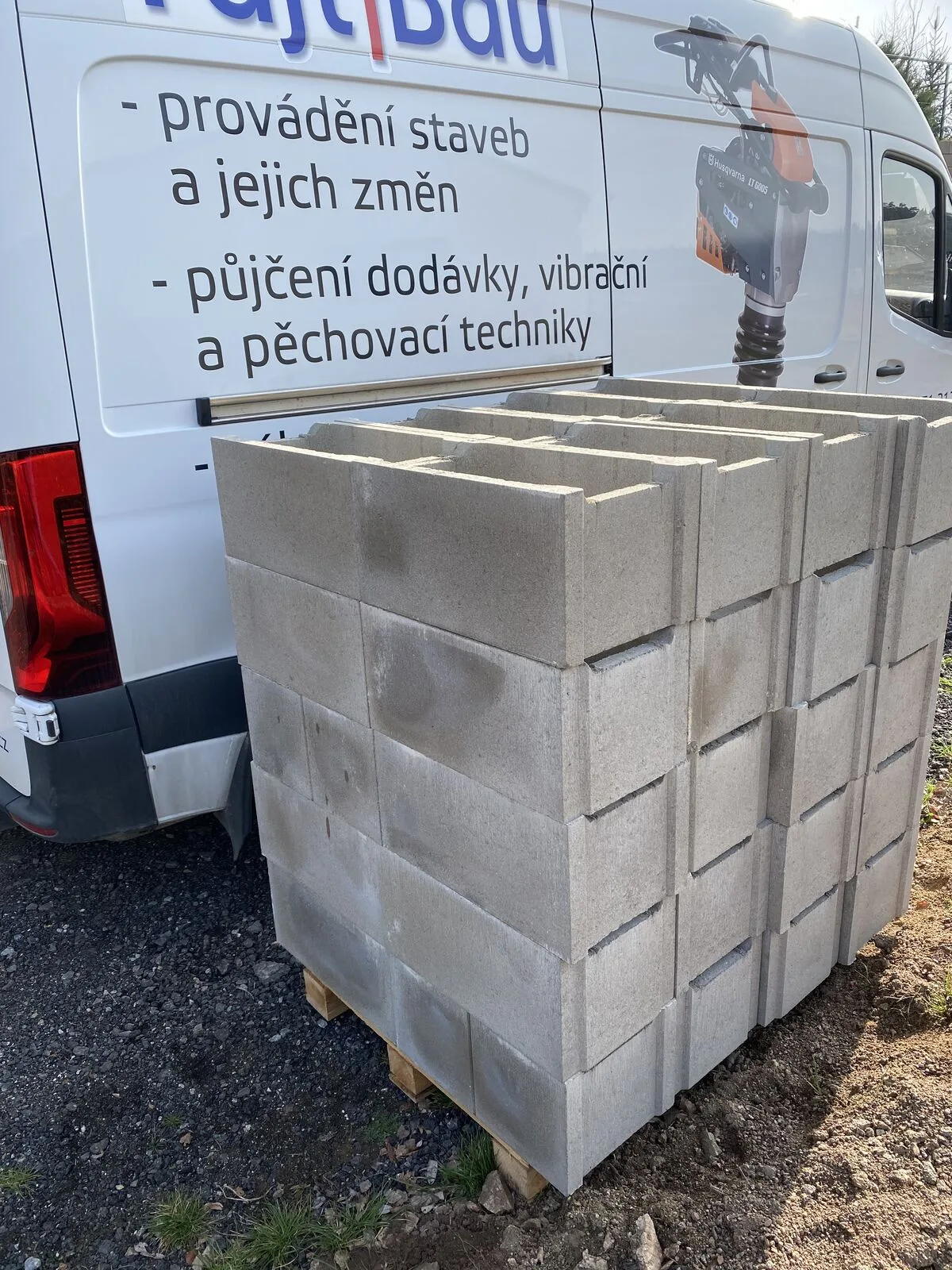 Otevřené zadní dveře dodávky FAJTBAU s nabídkou služeb, naložené palety